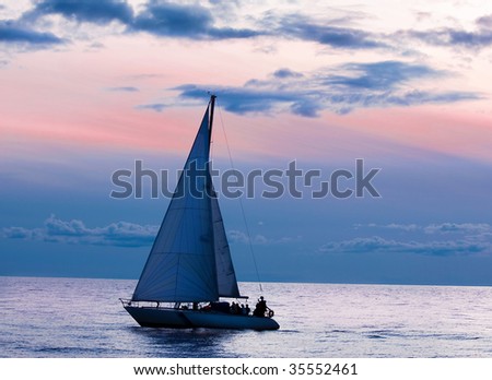 Sailboat at sunset in the ocean, stormy skies