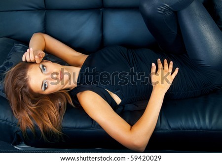 Pretty girl lays on the blue sofa.
