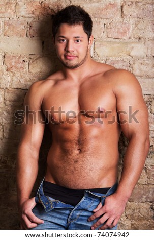 Portrait of a muscular man posing against old wall