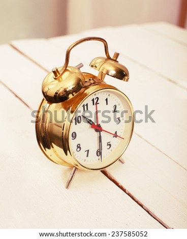 Image of gold alarm clock on the wooden table