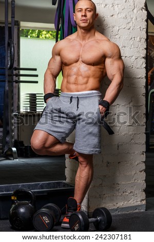 Strong muscular man bodybuilder poses and shows his trunk