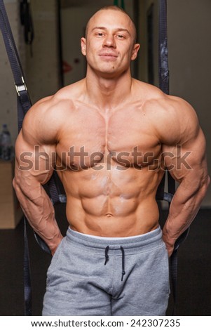Strong muscular man bodybuilder poses and shows his muscles