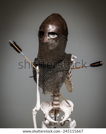 Skeleton of the dead warrior in the helmet and chain armour with arrows in his body