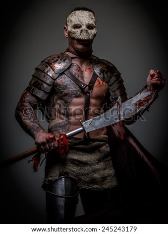 Gladiator in skull mask covered in armor holding sword