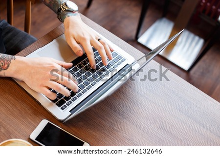 Picture of man\'s hands and fingers typing on laptop