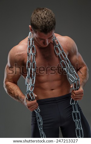Huge pumped male posing holding steel chain and showing his muscules