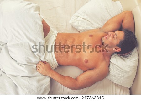 Attractive man lying in his bed smiling