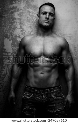 Fashionable muscular guy poses showing his body
