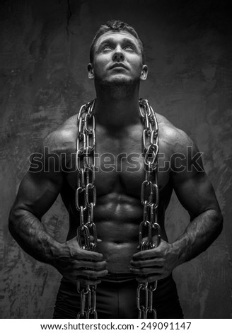 Muscular man with chain on gray background watching up.