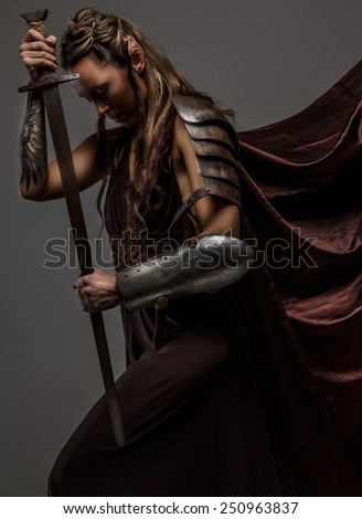Portrai of mystic  elf woman with sword, armor and tattoo on her hand. A side view portraite.