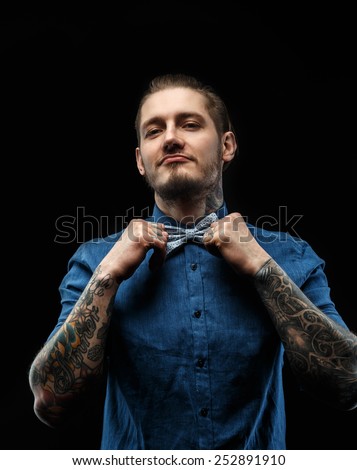 Portraite of a man with long hair and beard in blue shirt with tattooes on his hands.