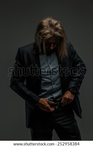 Portrait of handsome middle age long-haired stylish man in dark grey suit. Isolated on gray background.