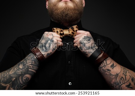 Part of face of the man with beard in black shirt and leopard bow tie. Isolated on dark gray background
