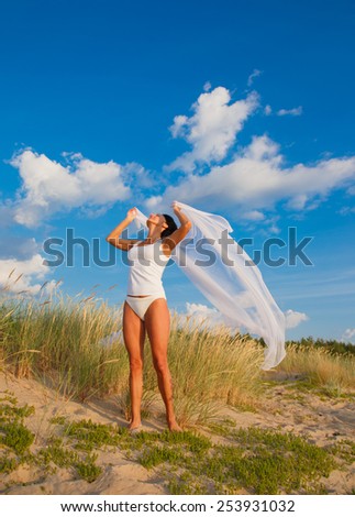 Middle age woman relaxing on a beach under blue sky.