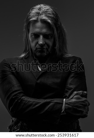 Black and white portrait of long hair middle age male possing in studio.