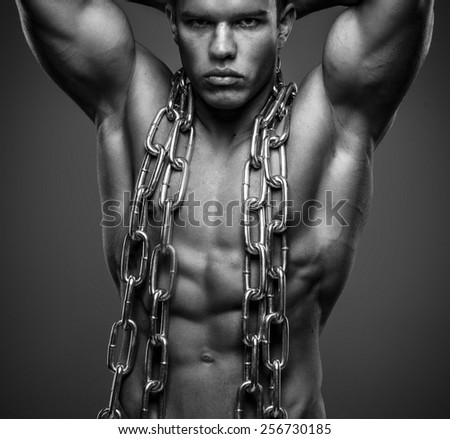Fashionable brutal guy with muscular body turned in steel chain