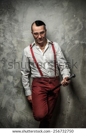 Male in red pants and white t shirt holding cane.