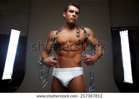 Portrait of awesome male model with naked muscular body. Isolated on dark grey background.