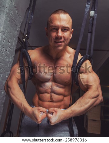 Strong muscular man bodybuilder poses and shows his abs and bicepses