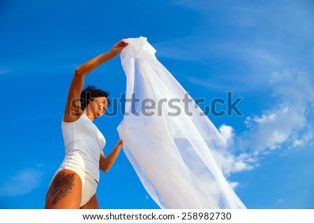 Middle age woman relaxing on a beach under blue sky.
