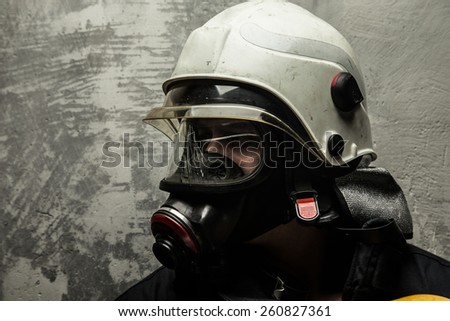 Male in oxygen mask and firefighter helmet on grey background