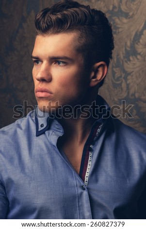 Fashion portrait of man in shirt poses over wall