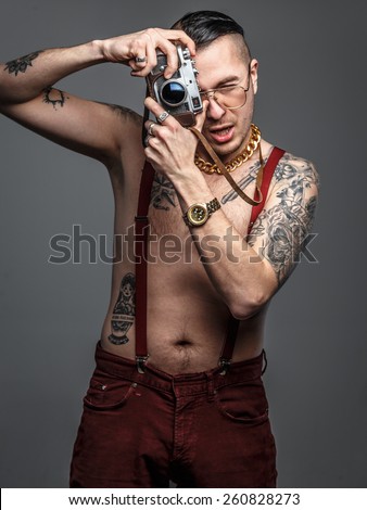 Male with tattoos holds photo camera.