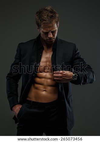 Muscular man in a suit posing in studio isolated on grey