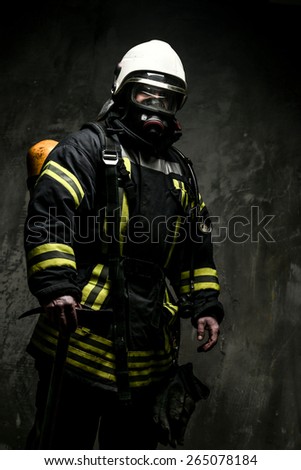 Firefighter in oxygen mask and axe on grey background.