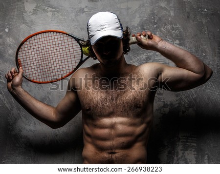 Male in white shorts with tennis racket over grey wall.