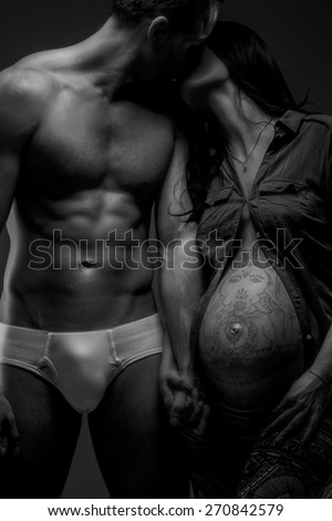 Naked man kissing his pregnant woman. Black and white photo