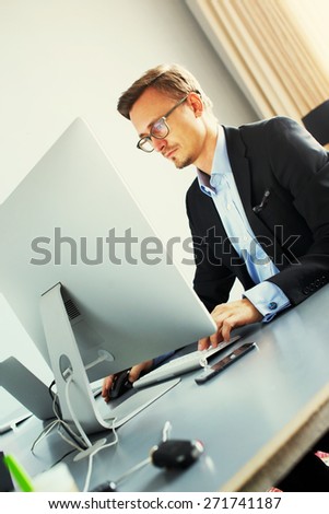 Handsome young business man working with computer in office.
