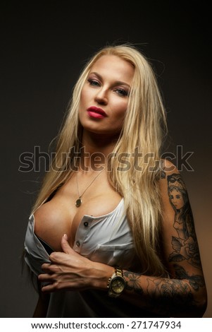Attractive modern blond female with tattoo on her hand. Isolated on grey
