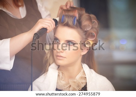 Blond female in hair salon. Hairdresser on background