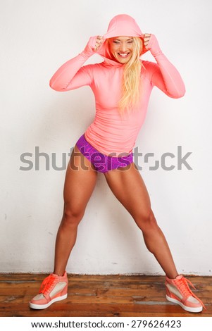 Blond female fitness model in sportswear posing on white background