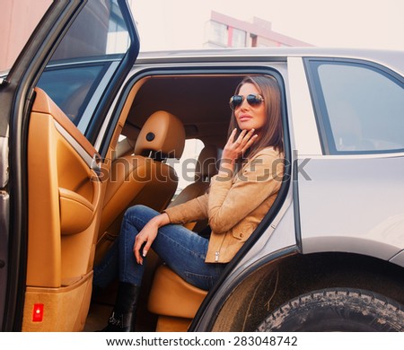 Seductive girl in sunglasses sitting in the car on back seats