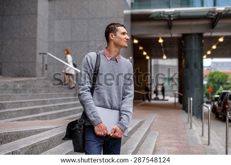 Guy on the modern street in casual clothing with laptop