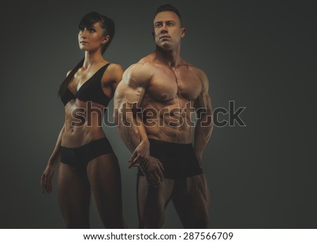Man and woman bodybuilders couple posing on grey background