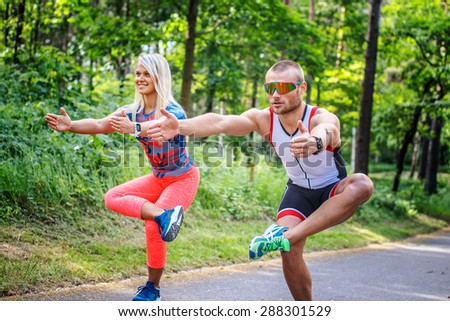 Man and woman in sportswear doing exercises on the forest road.