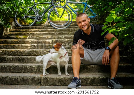 Man with dog sitting on stairs. Bicycles on background.