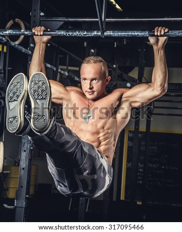 Awesome muscular man in military pants doing pull ups on horizontal bar.