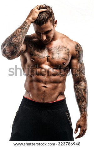 Shirtless muscular tattooed man isolated on white background.