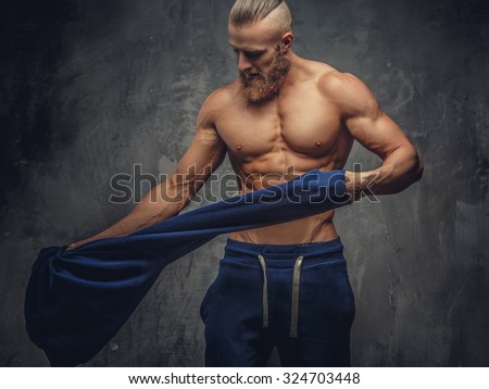 Muscular guy putting out blue sweater.
