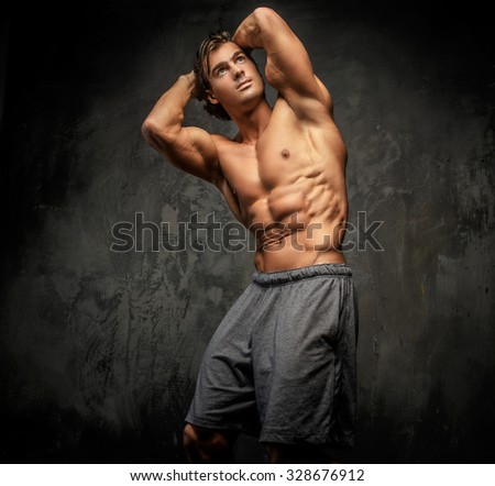 Shirtless muscular guy posing in studio and showing his great torso.