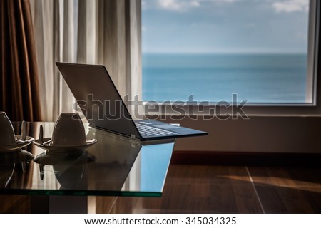 Thin laptop on glass table in modern apartments.