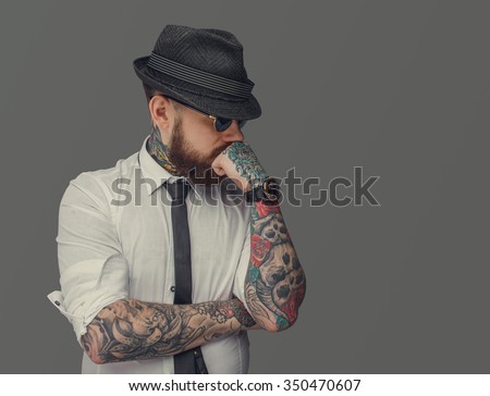 Man with tattooed arms thinking. Isolated on grey background.
