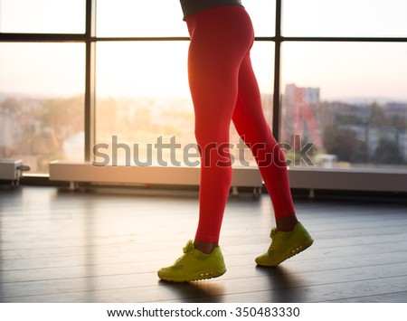 Woman\'s legs in red sports pants and yellow shoes.