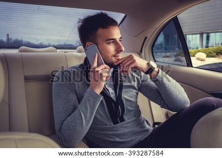 Casual man talking by smartphone in the car.