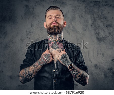 Studio portrait of bearded hipster man with tattoos on his arms, chest and neck.