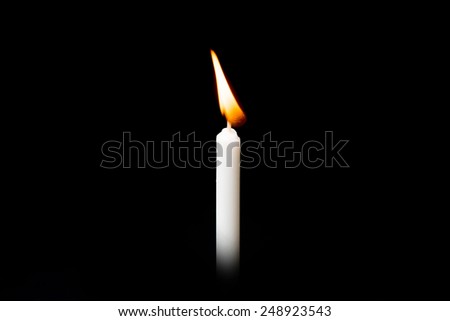Burning white candle on black background.